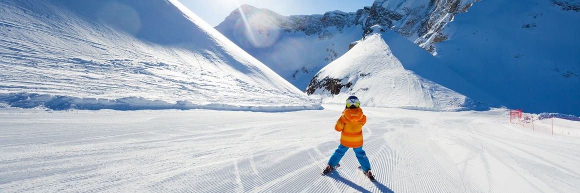 Enfant skiant vu de dos sur une piste vide d'autres skieurs